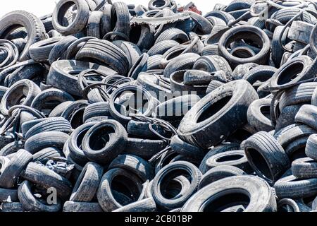 Pile assortite di pneumatici per auto vecchi e usati, che mostrano una varietà di modelli di battistrada in un deposito di pneumatici. Nessuna gente. Spazio di copia Foto Stock