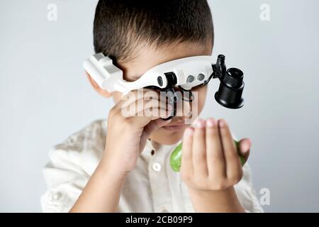 Un ragazzo in testa con lenti d'ingrandimento imparare incredibile chimica degli slime. Gioco tattile o sensoriale per i bambini più grandi Foto Stock