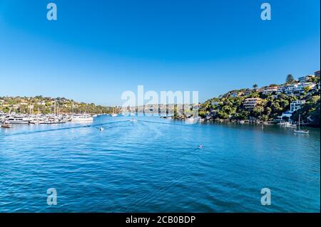 Spit West Reserve Blue Waters con barche ormeggiate su un lato e una zona residenziale sull'altro lato, tutti sullo sfondo Blur in un pomeriggio di sole inverno Foto Stock