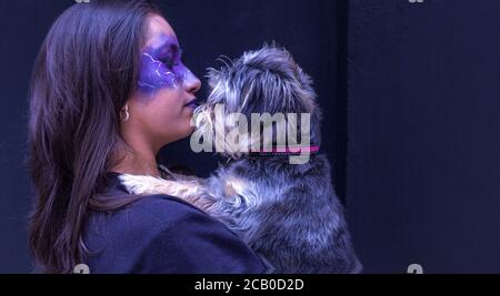 Ragazza teenage in trucco di Halloween con il suo cane su un sfondo scuro Foto Stock