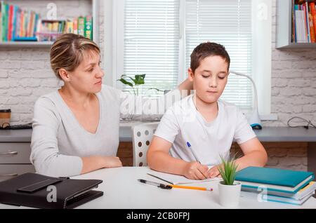 Il tutor è impegnato con il bambino, insegna a scrivere e contare Foto Stock