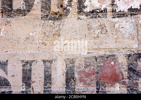 Vecchia tessitura della parete del mattone che mostra la scrittura grafica nera e l'alfabeto astratto della tipografia. Foto Stock