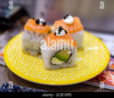 Sushi Roll con avocado al salmone e formaggio cremoso su un piastra gialla Foto Stock