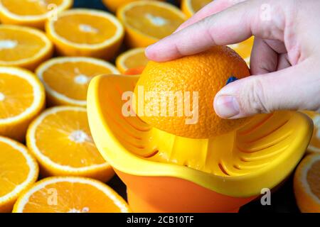 Succo d'arancia appena spremuto. Preparazione di un succo d'arancia fresco. Primo piano della mano che prepara un succo d'arancia spremuto. Centrifuga per agrumi Foto Stock