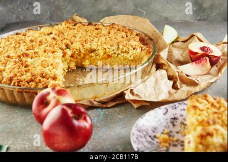 Torte fatte in casa, torta in una teglia con pesche e pere su cemento grigio-blu. Foto Stock