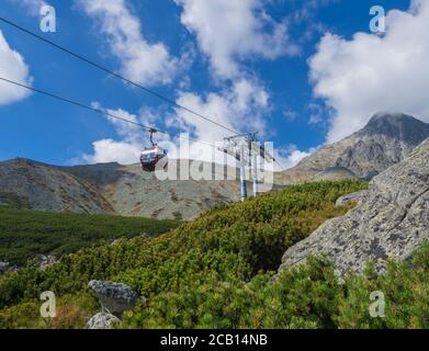 Slovacchia, alta montagna Tatra, 13 settembre 2018: Vista sulla montagna picco Lomnicky stit 2 634 m coperto di nuvole con funivia rossa cabina, scrub Foto Stock