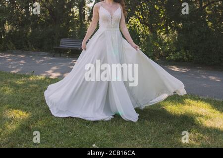 sposa in un abito da sposa vortici nel parco Foto Stock