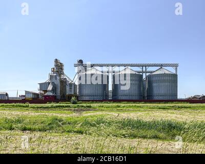 elevatore di grano, granaio. grandi torri di acciaio per immagazzinare i raccolti su fondo cielo blu chiaro Foto Stock
