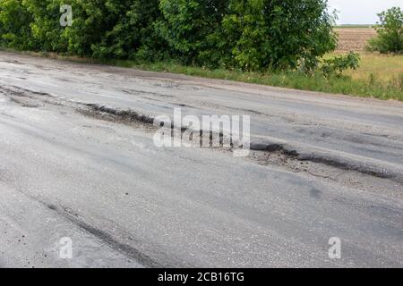 La strada è danneggiata, l'asfalto è rotto da camion. Foto Stock
