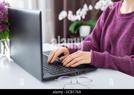 Donna che lavora o impara da casa utilizzando un computer portatile. I freelance hanno lavoro a distanza, webinar online di formazione a distanza. Le mani femminili che digitano sopra Foto Stock