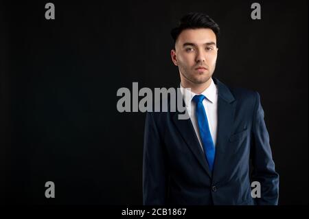 Ritratto di uomo d'affari che indossa un costume da lavoro blu e cravatta isolato su sfondo nero Foto Stock