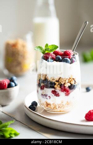 Bicchiere di parfait di granola, frutti di bosco e yogurt sul tavolo. Inquadratura ad angolo, vista ravvicinata, messa a fuoco selettiva. Foto Stock