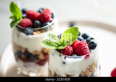 Due bicchieri di parfait di granola, frutti di bosco e yogurt sul tavolo. Vista ravvicinata, messa a fuoco selettiva. Foto Stock