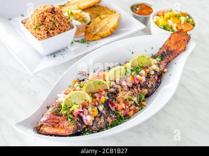 Piatto di pesce intero alla griglia con verdure e pezzi di limone in alto Foto Stock