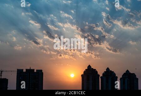 Mumbai, Maharashtra, India - Marzo 2020: Il sole brilla attraverso le nuvole dietro gli alti edifici del sobborgo di Kandivali a Mumbai. Foto Stock