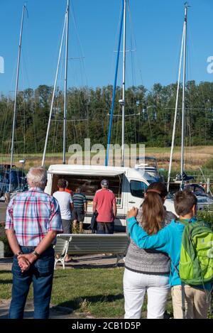 Baabe, Germania. 09 agosto 2020. Una lunga coda si è formata di fronte ad un carrello mobile per panettiere presso il porto di vela di Seedorf. Qui il 'Treppenbäcker' fornisce ai turisti panini freschi ogni mattina. Credit: Stefano Nosini/dpa-Zentralbild/ZB/dpa/Alamy Live News Foto Stock