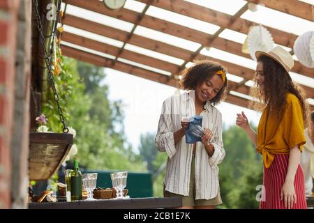 Vita in su ritratto di due donne sorridenti che strofinano gli occhiali mentre si preparano per la festa all'aperto in estate, copy space Foto Stock