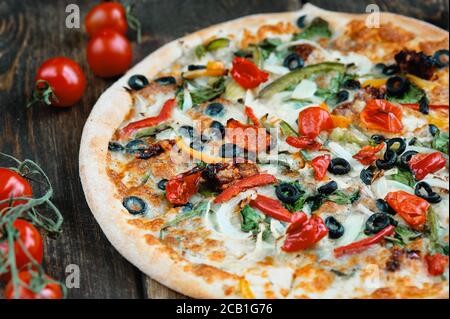 Deliziosa pizza fresca servita su tavola di legno. Cena estiva o pranzo. Pizza italiana vegetariana appena sfornata con verdure. Vista dall'alto. Foto Stock