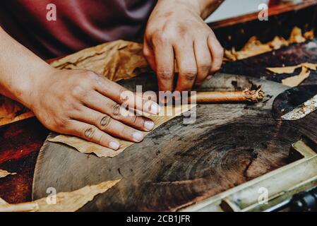 Primo piano delle mani rendendo il sigaro da foglie di tabacco. Produzione tradizionale di sigari. Repubblica Dominicana Foto Stock