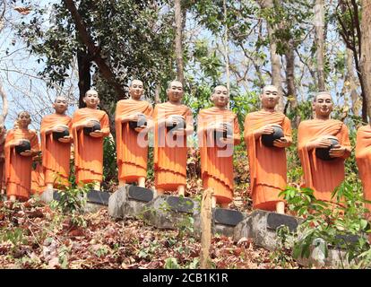 Statue di fila di monaci buddisti con ciotola di elemosina nel tempio di Dhama-Tibhathana (Dhama Dialogue Place), Cambogia, Asia Foto Stock