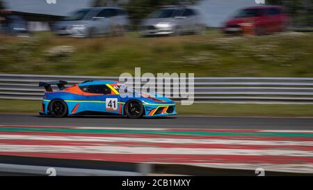 Una panoramica di una vettura da corsa blu e arancione mentre la pista è in pista. Foto Stock