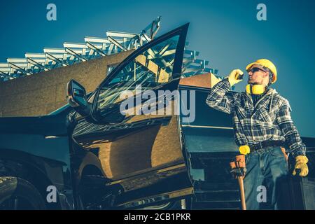 Contractor maschio di Medio Evo in piedi da camion di lavoro che parla su radio ricetrasmittente sul cantiere. Foto Stock