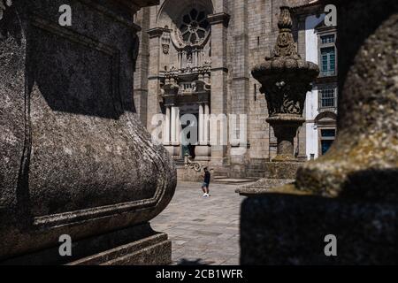 Un uomo con maschera protettiva passa accanto al sé do Porto, un edificio di struttura romana-gotica costruito nel XII secolo. Foto Stock