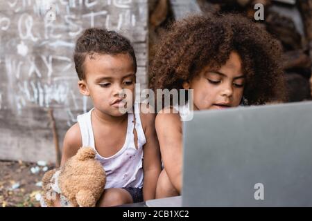 focalizzazione selettiva dei poveri bambini afro-americani che guardano al laptop esterno Foto Stock
