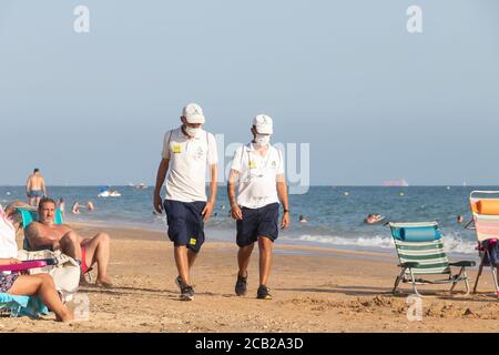 Punta Umbria, Huelva, Spagna - 7 agosto 2020: Guardia di sicurezza della spiaggia di Junta de Andalucia sta controllando l'allontanamento sociale e l'uso della maschera protettiva Foto Stock