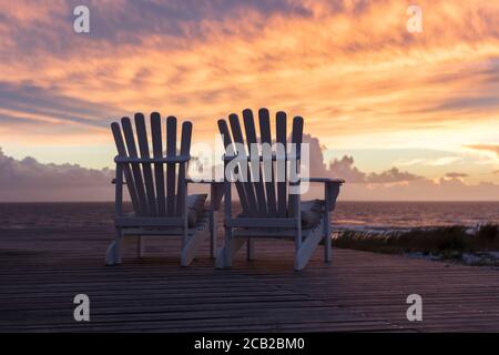 Due sedie vuote affacciate sulla magnifica vista del tramonto sulla spiaggia Foto Stock