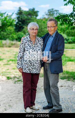 Ritratto a corpo pieno di una coppia di 80 anni in pensione in un parco estivo, che guarda amichevole nella fotocamera. Foto Stock