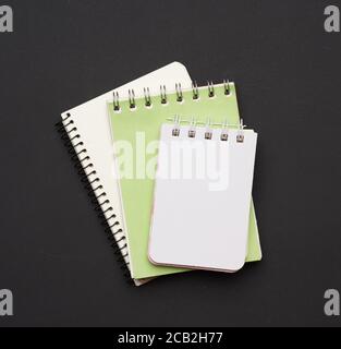 pila di notebook aperti a spirale con fogli bianchi vuoti su sfondo nero, vista dall'alto Foto Stock