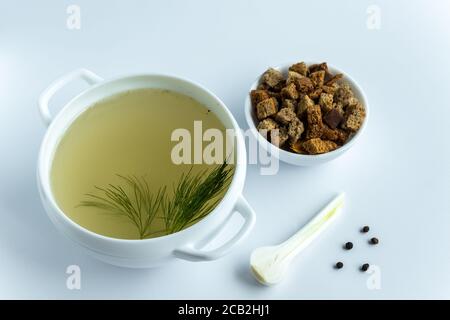 Brodo di ossa di carne fatto in casa in un tureen con aneto. Crostini e spezie su fondo bianco. Concetto di cibo sano. Dieta di Paleo. Vista dall'alto. Spazio di copia Foto Stock