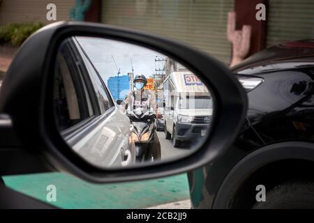 Specchio ad ala riflesso di un'auto che mostra un poliziotto seguente su una motocicletta. Thailandia, Sud-est asiatico Foto Stock