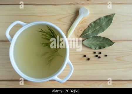 Brodo fatto in casa di ossa di carne in un tureen, condimenti e verdure, su un legno background.concetto di cibo sano. Paleo diet.fuoco selettivo.Vista dall'alto. Foto Stock