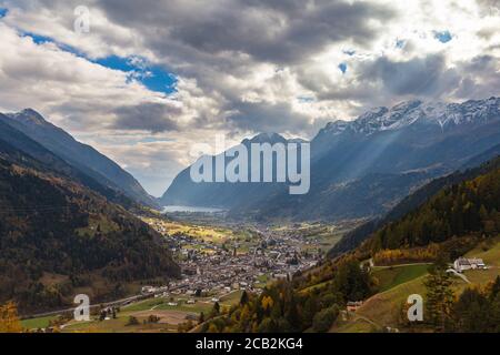 Splendida vista panoramica aerea della città di Poschiavo in valle con le Alpi svizzere e il lago di Poschiavo sullo sfondo, in autunno sulla ferrovia turistica l Foto Stock