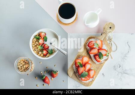 Concetto di colazione salutare. Toast con formaggio casolare e fragola, yogurt con muesli e tazza di caffè su tricolore sfondo elegante, vista dall'alto Foto Stock