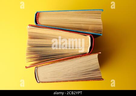 Libri vecchi e usati o libri di testo visti dall'alto. Libri su sfondo giallo. Foto Stock