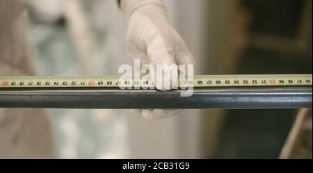 Addetto alla costruzione che utilizza un nastro di misurazione. Primo piano Foto Stock