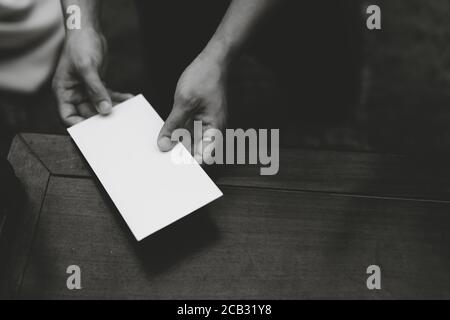 Primo piano sulle mani di una persona che consegna una busta vuota (foto in bianco e nero) Foto Stock