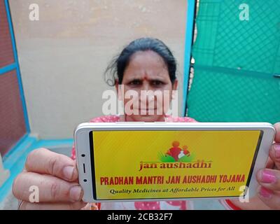 DISTRETTO KATNI, INDIA - 23 MAGGIO 2020: Donna che tiene uno smartphone con visualizzazione pradhan mantri jan aushadhi yojana schema sullo schermo. Governo indiano Foto Stock