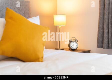 camera da letto con cuscino giallo e sveglia Foto Stock