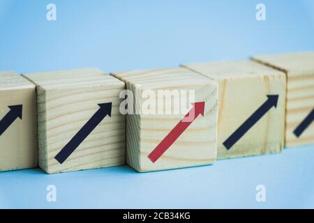 primo piano di blocchi di legno con frecce nere e rosse su sfondo blu, concetto di leadership Foto Stock