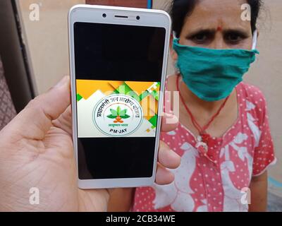 DISTRETTO KATNI, INDIA - 23 MAGGIO 2020: Donna che tiene uno smartphone con visualizzazione pradhan mantri jan arogya yojana pmjay schema sullo schermo. Governo indiano Foto Stock