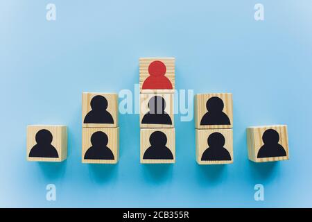 vista dall'alto dei blocchi di legno con icone umane nere e rosse su sfondo blu, concetto di leadership e scala di carriera Foto Stock