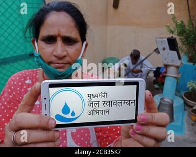 DISTRETTO KATNI, INDIA - 23 MAGGIO 2020: Donna che tiene uno smartphone con mukhyamantri jal Swavalamban Yojana schema visualizzato sullo schermo. Governo indiano Foto Stock