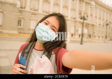 Nuovi viaggi vacanze normali in Europa - giovani felici e. Bella donna turistica giapponese asiatica indossando maschera prendendo selfie con telefono cellulare con ci Foto Stock