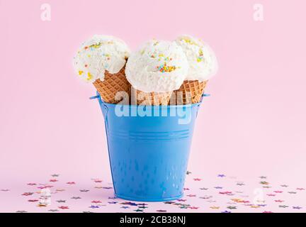 Coni gelato in un secchio blu su sfondo rosa decorato con stelle. Un cono gelato in stile wafer. Foto Stock