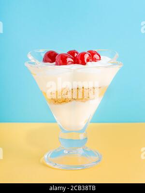 Un dessert di panna montata, yogurt greco, gelato e biscotti con amarena in un bicchiere. Foto Stock