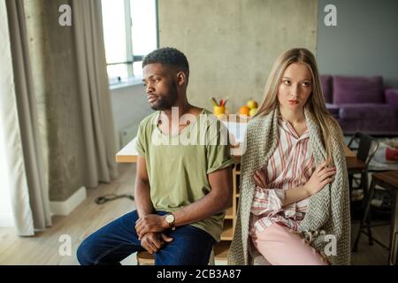 Giovane coppia infelice interracial che ha problemi nel rapporto, seduto in soggiorno a casa Foto Stock